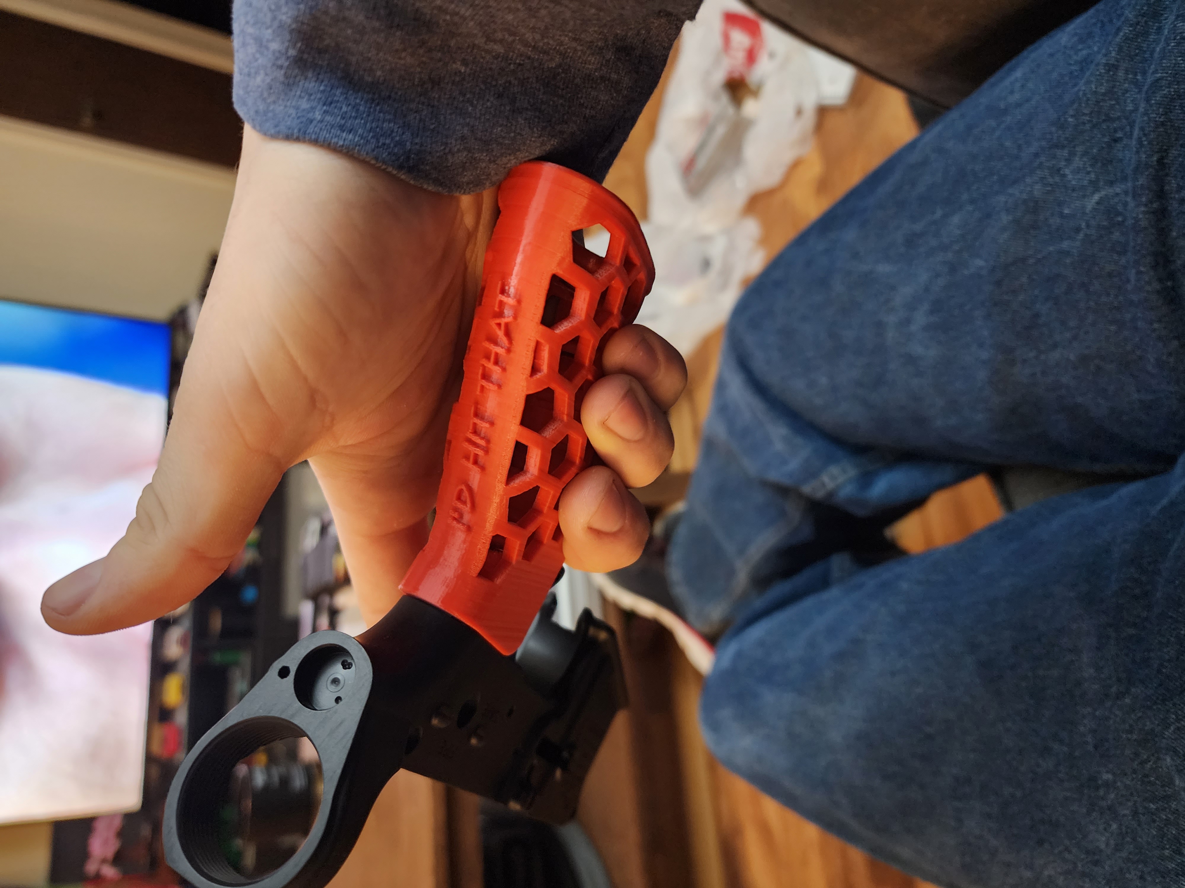 Red 3D printed vertical foregrip with hex cutouts and embossed lettering